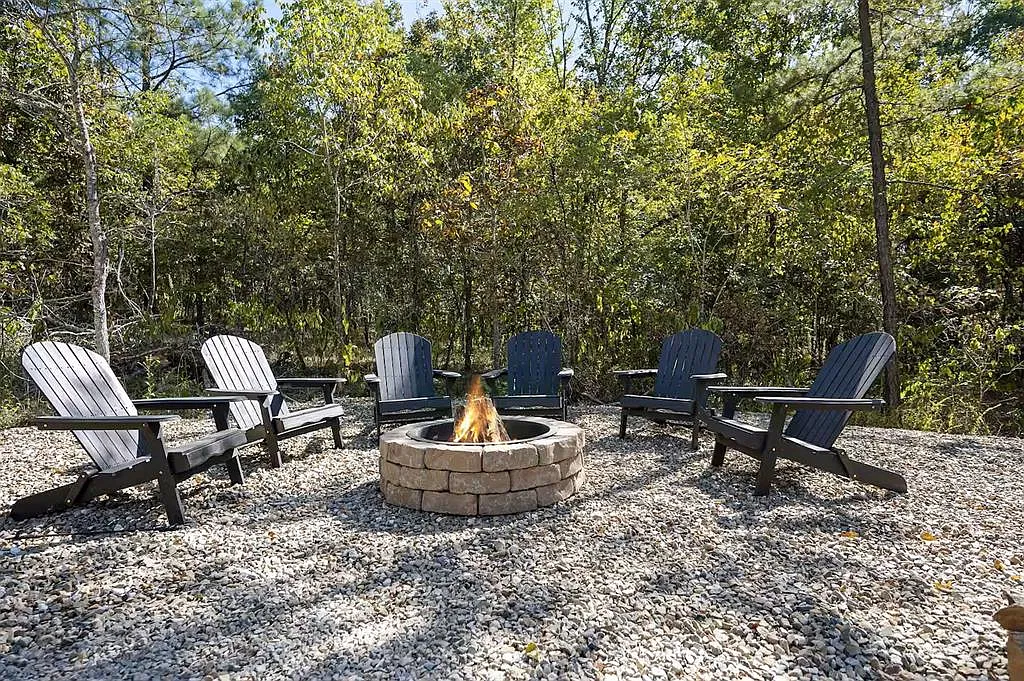 Fire pit ringed with Adirondack chairs in the trees